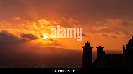 Lyme Regis, dans le Dorset, UK. 11 octobre 2018. Météo France : toits dans le quartier historique de la ville de Lyme Regis sont silhouetté contre moody ciel comme les nuages de tempête orange glow au lever du soleil sur ce qui est défini pour être un jour pluvieux et venteux à Lyme Regis. Credit : PQ/Alamy Live News Banque D'Images