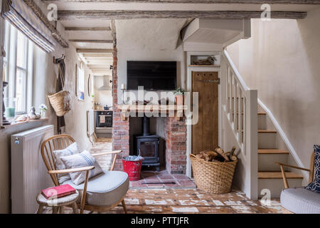 Fauteuil de style dépouillé Ercol et plat fixé au mur au-dessus de cheminée en brique de plain Banque D'Images