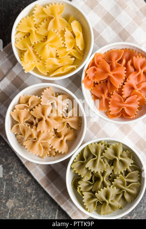 Pâtes Farfalle. Les pâtes italiennes colorés dans un bol sur la vieille table de cuisine. Banque D'Images