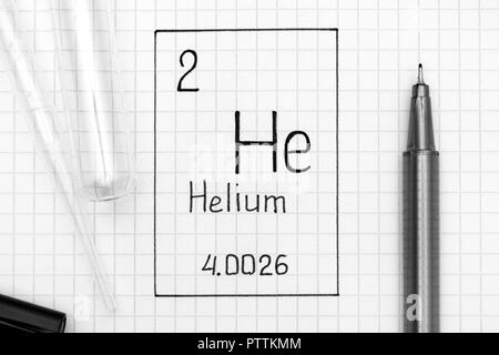 Le tableau périodique des éléments. Il l'hélium à l'élément chimique de l'écriture avec un stylo noir, tube à essai et pipette. Close-up. Banque D'Images