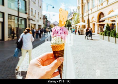 Man Holding Green pistache et framboise Rose cornet de crème glacée dans la main Banque D'Images