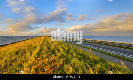 Afsluitdijk dutch endiguer à l'autoroute et piste cyclable pendant le coucher du soleil avec ciel assombri Banque D'Images