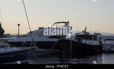 Matin au port croate à Brela. Dans le ciel il y a des nuages éclairés par le soleil levant. Bateaux et yachts sont garées dans le port. Banque D'Images