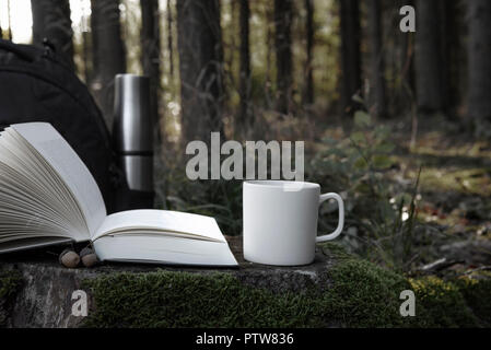 Dans la forêt des paysages avec un livre ouvert et une tasse de café blanc sur une souche d'arbre dans une journée ensoleillée d'octobre Banque D'Images