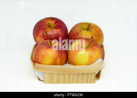 Une vue rapprochée d'un panier avec quatre pommes dans une vaste, propre et fond blanc Banque D'Images