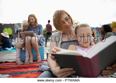 Mother and Daughter reading book in park