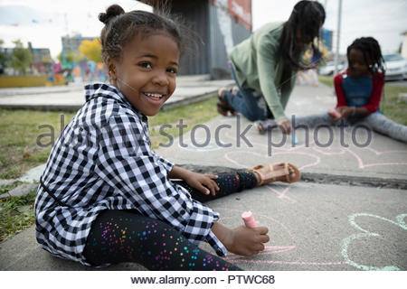 Portrait of smiling, jolie fille dessin avec craies de trottoir