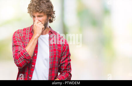 Beau modèle hispanique homme sur fond isolé humer un stinky et dégoûtant, odeur insupportable, apnée avec les doigts sur le nez. Banque D'Images