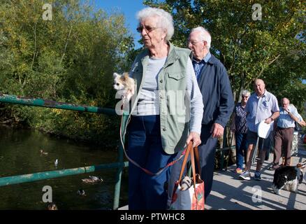 Une vieille dame porte un petit chien sur un pont sur la rivière Wye de Bakewell, Derbyshire Banque D'Images