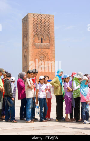 Les étudiants se sont alignés pour visiter la Tour Hassan, un minaret mosquée inachevée avec en arrière-plan, à Rabat, au Maroc. Banque D'Images