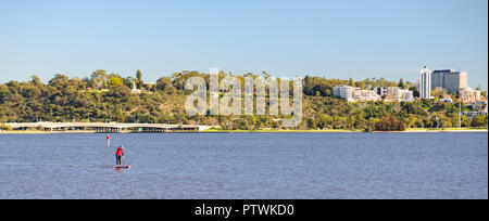 Man Stand up Paddling en face de la skyline de Perth avec Swan River. Vue depuis le Sud Perth, Perth, Australie occidentale Banque D'Images