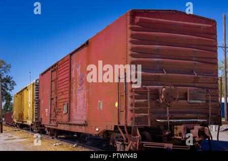 Vue avant du vieux rouge et jaune rouille chargement de wagons de chemin de fer avec des portes fermées, stationné sur la ligne ferroviaire Banque D'Images