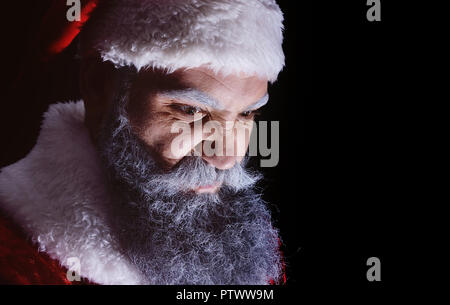 Le mal du Père Noël, grimaces et fait peur à terrible visage sur un fond sombre Banque D'Images