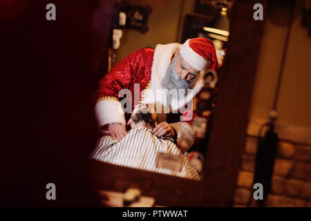 Père Noël Coiffure Coupe et rase la barbe d'un homme dans un salon de coiffure Banque D'Images