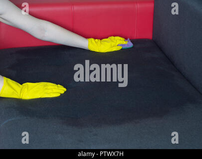 Fille dans le canapé jaune nettoie des gants, close-up Banque D'Images