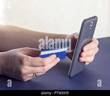 Girl entre des données dans le téléphone avec une carte de crédit, close-up Banque D'Images