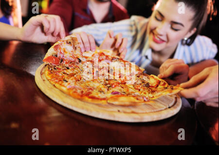 Un groupe d'amis manger une pizza dans un bar ou une pizzeria. Banque D'Images