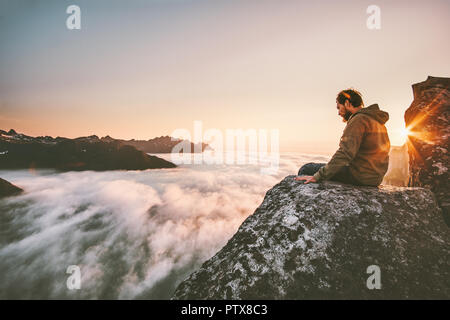 La pensée de l'homme siégeant seul sur falaise montagne nuages au-dessus de l'aventure voyage solitude vie émotions extrêmes de survie vacations Banque D'Images