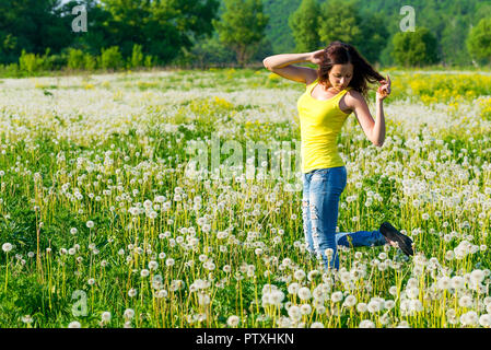 La femme marche sur un terrain vert avec des pissenlits Banque D'Images