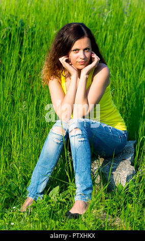 jeune femme mignonne brune femme assise sur la pierre regardant appareil photo Banque D'Images