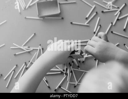 Un petit enfant joue avec des allumettes, allumettes prend à partir de la table, close-up, noir et blanc, feu, des allumettes et de l'enfant Banque D'Images