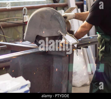 La production de fenêtres en PVC, un homme coupe un profil sur une scie circulaire, close-up, profile Banque D'Images