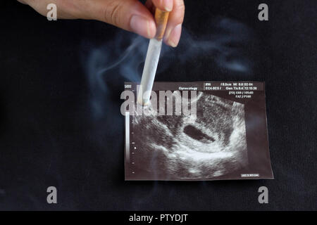 A woman's hand, une future mère s'éteint une cigarette sur la photo d'une grossesse La grossesse et l'uzi, fumeurs de cigarettes, et la grossesse Banque D'Images