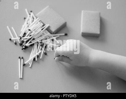 Un petit enfant joue avec des allumettes, allumettes prend à partir de la table, close-up, noir et blanc, feu, des allumettes et de l'enfant Banque D'Images