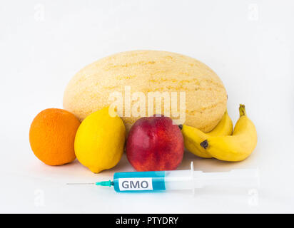 Fruits sur un fond blanc banane, orange, citron, melon et nectarine, next est une seringue d'OGM et de dérivés nitrés, organisme génétiquement modifié, des fruits Banque D'Images