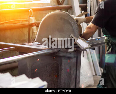 La production de fenêtres en PVC, un homme coupe un profil sur une scie circulaire, close-up, profile Banque D'Images