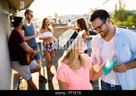 Les amis de s'amuser et de boire des cocktails en plein air, sur un toit se réunir Banque D'Images