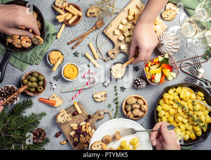 Mise à plat de fête Noël avec dîner table et des mains humaines, l'alimentation végétarienne de l'arrière-plan, Vue de dessus concept Banque D'Images