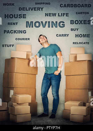 Full Length portrait of young man leaning on boîtes de carton jusqu'à la réflexion. Concept de maison d'emballage, de trucs plus isolés de mur gris. Banque D'Images