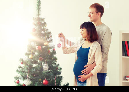 Heureux femme enceinte et mari at Christmas Tree Banque D'Images