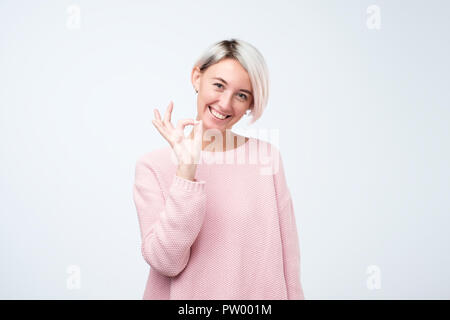 Young adult woman court avec les cheveux colorés montrant ok signe. Expression de l'émotion et les sentiments concept. Banque D'Images