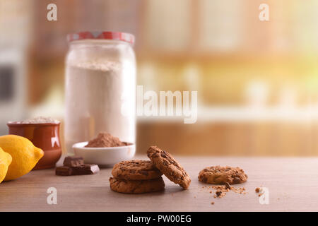 Des biscuits aux pépites de chocolat sur la table en bois avec ingrédients dans une cuisine rustique. Composition horizontale. Vue avant Banque D'Images