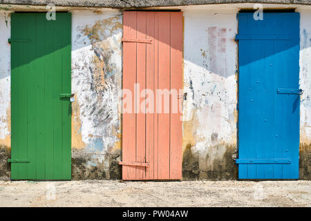 Vert et rose et bleu de vieilles portes en bois sur le mur de lumière minable contexte extérieur. Soleil brille sur eux. L'horizontale. Banque D'Images