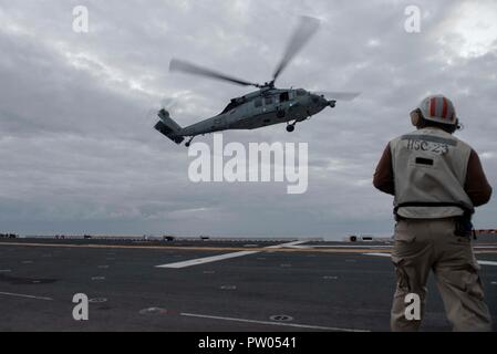 181011-N-FF029-1014, OCÉAN PACIFIQUE (oct. 11, 2018) Chef Technicien en électronique d'aviation, Polk Roosevelt de Crestview, Fla., affecté à la "Jokers" de l'Escadron d'hélicoptères de combat de la mer (HSC) 23, un coordonnateur d'envol, observe un MH-60S Sea Hawk le décollage de l'envol du navire d'assaut amphibie USS Bonhomme Richard (DG 6). Bonhomme Richard fonctionne aux États-Unis Flotte 3ème zone d'opérations. (U.S. Photo par marine Spécialiste de la communication de masse 3e classe Daniel Charest) Banque D'Images