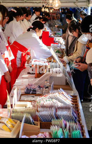 Nouvel An japonais, shogatsu. Shrine Maidens, Miko, au comptoir de vente de divers types d'omamori, bonne chance aux gens à charmes Ikuta de culte. Banque D'Images