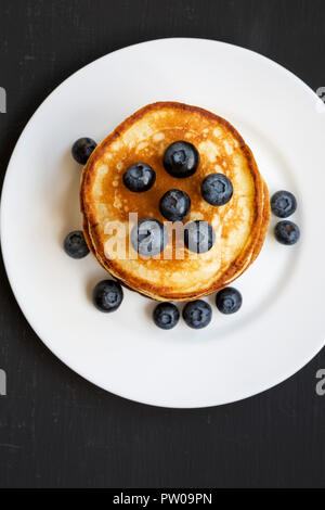 Crêpes aux bleuets sur une plaque ronde blanche sur fond noir, vue de dessus. Close-up. Mise à plat, vue d'en haut, d'en haut. Banque D'Images