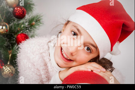 Fille avec veste blanche et with santa hat smiling in studio Banque D'Images