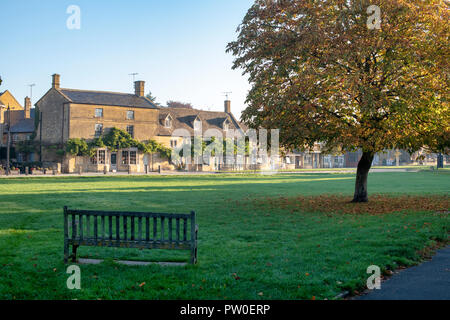 Cotswold boutiques / maisons face au village vert dans l'automne tôt le matin du soleil. Broadway, Cotswolds, Worcestershire, Angleterre. Banque D'Images