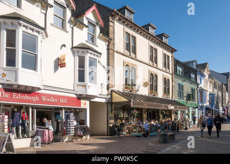 Personnes à pied et à l'extérieur assis dans un café dans la rue principale de Keswick, Cumbria, England, UK Banque D'Images