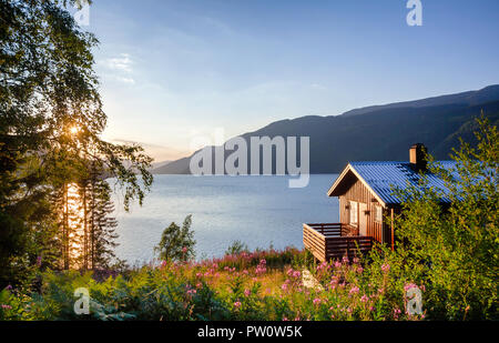 Maison d'été en bois norvégienne (Hytte) avec terrasse donnant sur le pittoresque lac au coucher du soleil, Telemark, Norvège, Scandinavie Banque D'Images