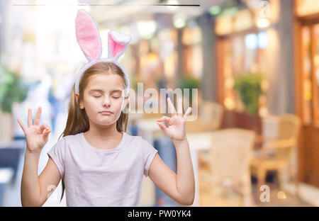 Belle jeune fille portant des oreilles de lapin de Pâques sur fond isolé vous détendre et souriant avec les yeux fermé faisant le geste de la méditation avec les doigts. Le Yoga Banque D'Images