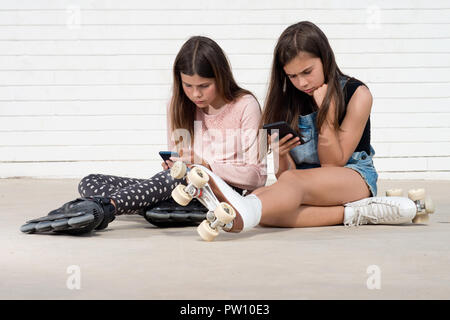 Deux patineurs les filles à la recherche d'une son smartphone Banque D'Images