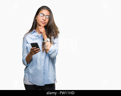 Belle jeune femme arabe à l'aide de SMS sur smartphone fond isolé visage sérieux de penser à question, idée très confus Banque D'Images