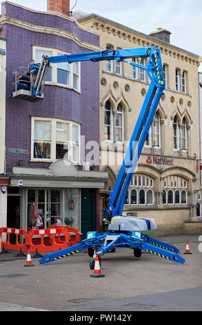 Les travailleurs utilisant un Genie TZ-50 boom montés sur remorque pour fixer le câble en acier dans les bâtiments pour les décorations de Noël dans la région de Wells, Somerset, Royaume-Uni. Banque D'Images