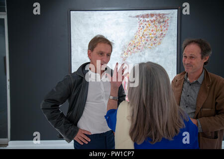 Johannesburg, Afrique du Sud, 11 octobre 2018. Guy Ferrer (L) parle à un visiteur qu'il ouvre son spectacle Feu Sacré (Feu Sacré) jeudi soir à la galerie Everard Read à Johannesburg, Afrique du Sud. 'Le feu sacré est l'irrépressible et permanent besoin de continuer à travailler dans mon atelier, chaque seul jour, au point de se sentir coupable lorsque pour une raison ou une autre, je dois m'arrêter", dit le peintre et sculpteur dans sa démarche artistique pour le spectacle. Ferrer, qui est né en Algérie, vit et travaille à Paris, France. Credit : Eva-Lotta Jansson/Alamy Live News Banque D'Images