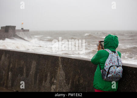 Porthcawl, Pays de Galles, Royaume-Uni. Vendredi 12 octobre 2018. Une jeune femme prend une photo que Storm Callum batters le phare à Porthcawl en Galles du sud : Crédit Gruffydd Thomas/Alamy Live News Banque D'Images